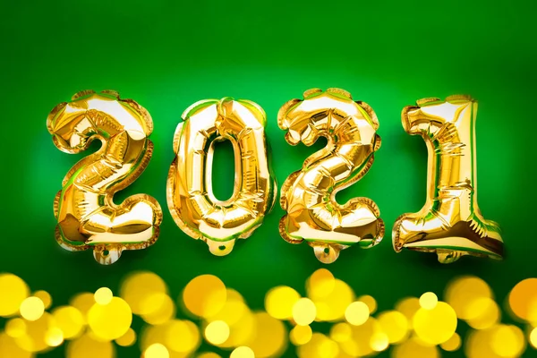 Feliz Ano Novo 2021 celebração. Balões de folha de ouro numeral 2021 e luzes festivas bokeh no fundo verde. Depósito plano — Fotografia de Stock