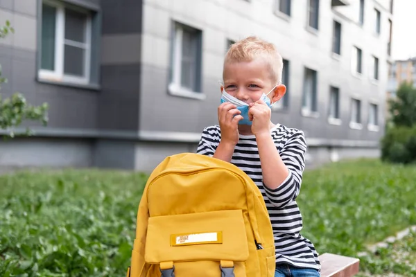 Terug naar school. Happy Boy met masker en rugzakken beschermen en beschermen tegen het coronavirus. Een kind dat vlak na de pandemie bij school zat. studenten zijn klaar voor nieuw jaar — Stockfoto