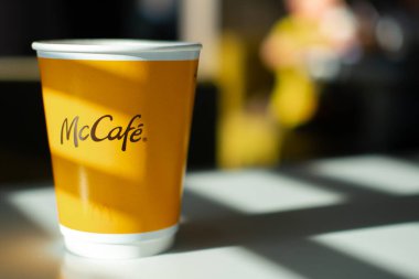 McDonalds restoranında McCafe menüsü. Masada sarı kahve fincanı ve güneşten gelen gölgeler. Kahvaltı zamanı, kahve zamanı. Finlandiya, Vantaa, 28 Şubat 2020