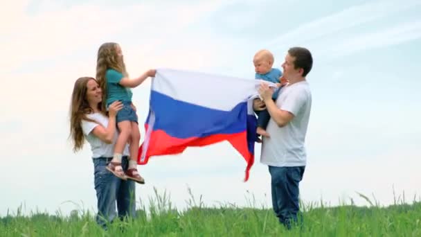 4k. Gelukkige familie moeder vader en twee kinderen meisje en kleine jongen zwaaien nationale Rusland vlag buiten groen gras blauwe hemel in de zomer - Russische vlag, land, patriottisme, Rusland dag en 12 juni. — Stockvideo