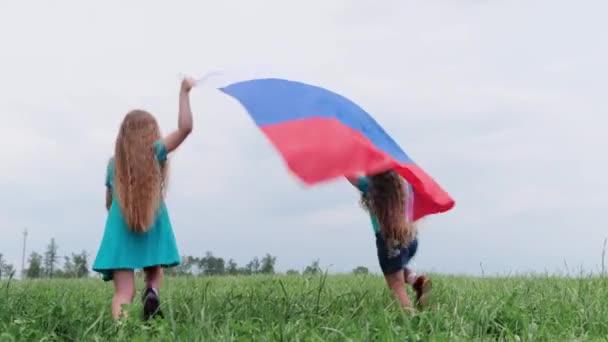 4K. Duas irmãs se divertindo acenando bandeira nacional da Rússia ao ar livre correndo na grama verde no verão bandeira russa, país, patriotismo, dia da Rússia — Vídeo de Stock