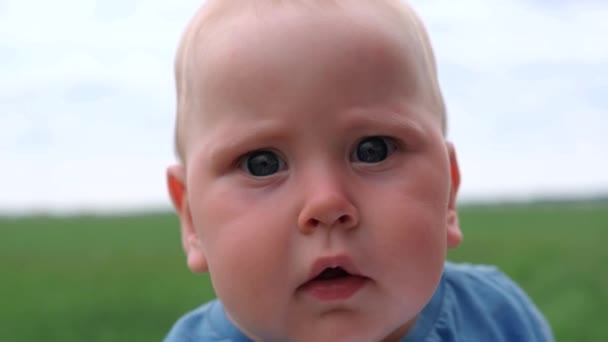 4k. Close up Serious Infant boy smiling, laughing and looking at camera. Mom holding baby on hands over blue cloudy sky at summer. Happy childhood and family concept. — Stock Video
