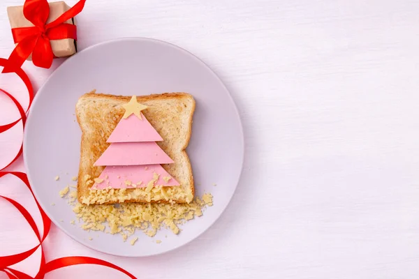 Sanduíche engraçado com árvore de Natal comestível feita de pão torrado, salsicha e queijo. Ideia de pequeno-almoço para crianças. Ano Novo comida vista de fundo superior. feriado, celebração, conceito de arte alimentar. — Fotografia de Stock