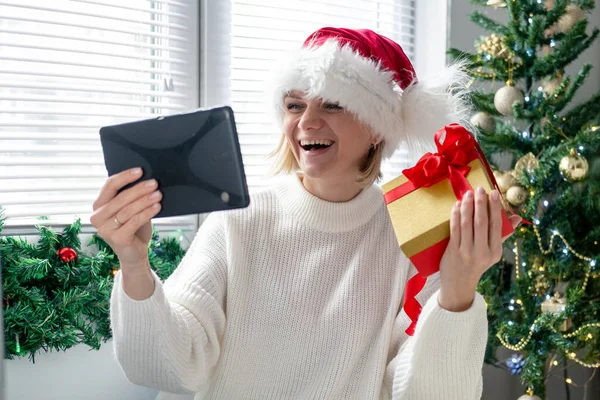 Julen online grattis. Leende kvinna som använder mobil surfplatta för videosamtal vänner och föräldrar — Stockfoto