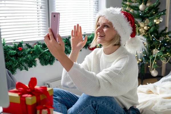 Boże Narodzenie online gratulacje. Uśmiechnięta kobieta korzystająca z telefonu komórkowego do rozmów wideo z przyjaciółmi i rodzicami — Zdjęcie stockowe