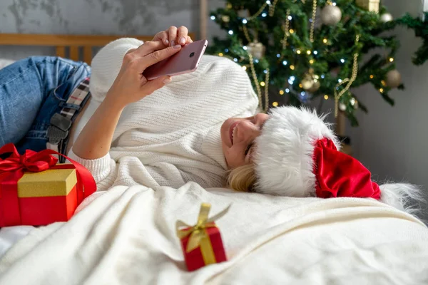 Boże Narodzenie online gratulacje. Uśmiechnięta kobieta korzystająca z telefonu komórkowego do rozmów wideo z przyjaciółmi i rodzicami — Zdjęcie stockowe