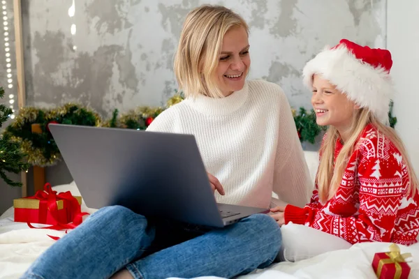 Noel aile içi tebrikleri. Gülümseyen Avrupalı sarışın anne-kız video görüşmesi için mobil tablet kullanıyor.