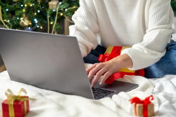 Świąteczne zakupy online. Dziewczyna robi porządek na laptopie. Kobieta kupuje prezenty, przygotowuje się do świąt, wśród pudełek i opakowań. Sprzedaż wakacji zimowych. — Zdjęcie stockowe