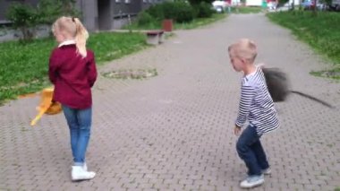 Okula dört bin dolar. Çocuklar sokakta oynuyor, sarışın çocuk ve kız sırt çantalarıyla dönüyorlar..