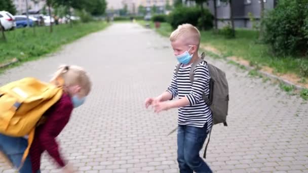 4k torna a scuola. bambini che giocano per strada. I bambini che indossano maschera e zaini proteggono e sicurezza coronavirus. Ragazzo e ragazza andare a scuola dopo pandemia oltre. — Video Stock