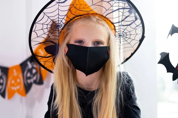 Retrato de chica rubia en traje de bruja con mascarillas preparándose para Halloween protegiendo de COVID-19 —  Fotos de Stock