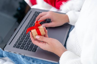 Noel alışverişi. Kadın alıcı dizüstü bilgisayardan sipariş veriyor. Kadın hediyeler alır, Noel 'e hazırlanır, hediye kutuları ve paketlerin arasında. Kış tatili satışları.