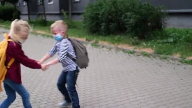 Okula dört bin dolar. Çocuklar sokakta oynuyorlar, sırt çantalarıyla dönüyorlar. Maske takan çocukların koronavirüsü. Oğlan ve kız salgın hastalık üstüne okula gidiyorlar.. 