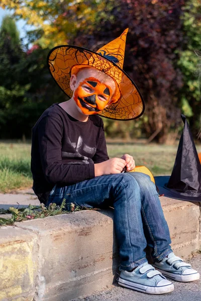 Niños de Halloween. Retrato Niño risueño con mascarilla de calabaza en traje de bruja sombrero con cubo de caramelo en la calle —  Fotos de Stock