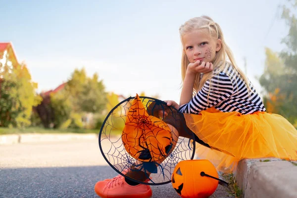 Niños de Halloween. chica sonriente en sombrero de bruja con cubo de caramelo de calabaza. Niños divertidos en trajes de carnaval al aire libre —  Fotos de Stock