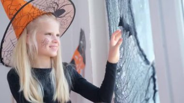 4 bin. Cadılar Bayramı için hazırlanan cadı kostümlü mutlu kız siyah yarasaların odadaki pencerelerini süslüyor.