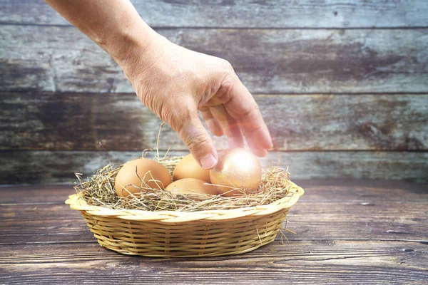 hand pickup golden  eggs on and normal egg in the basket on the table