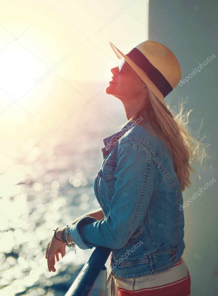 Happy blonde woman in hat enjoying the sunshine at sea, vintage