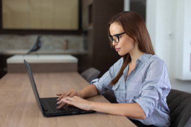 Genç casual esmer kadın evde dizüstü bilgisayarda yazarak