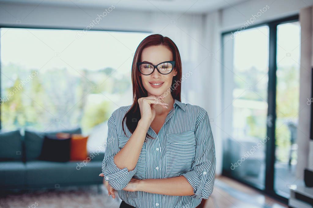 Young confident smart woman posing in living room indoors