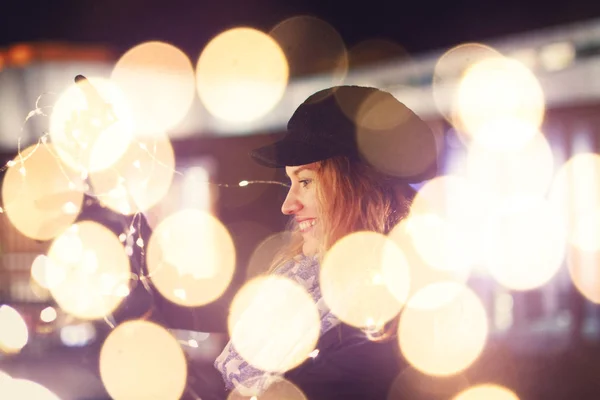 Young woman playing with fairy lights at winter outdoors