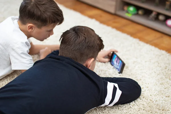 Kleine Jungen sehen Video per Smartphone auf Teppich — Stockfoto