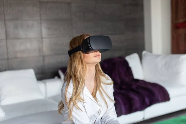 Young blonde woman with VR headset at home, virtual reality