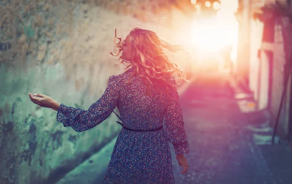 Young carefree woman walking on mediterranean street in sunset — Stock Photo, Image