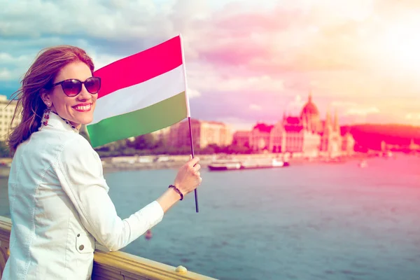 Happy young woman holding Hungarian flag at Budapest in sunset