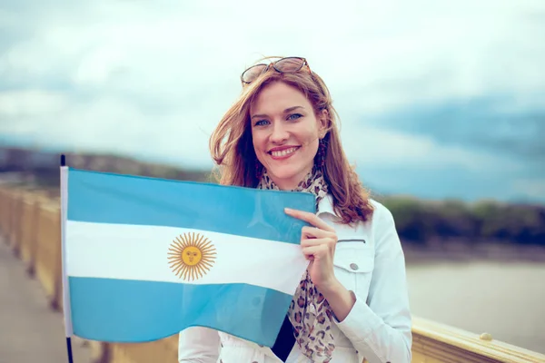 Happy young woman holding flag of Argentina on bridge — Stock Photo, Image