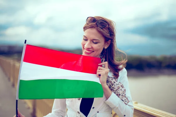 Joyeux jeune femme regardant et tenant drapeau hongrois — Photo