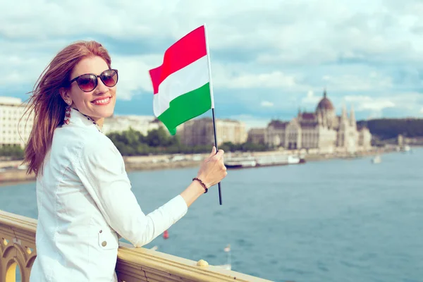 Happy young redhead hungarian woman holding hungarian flag at Bu