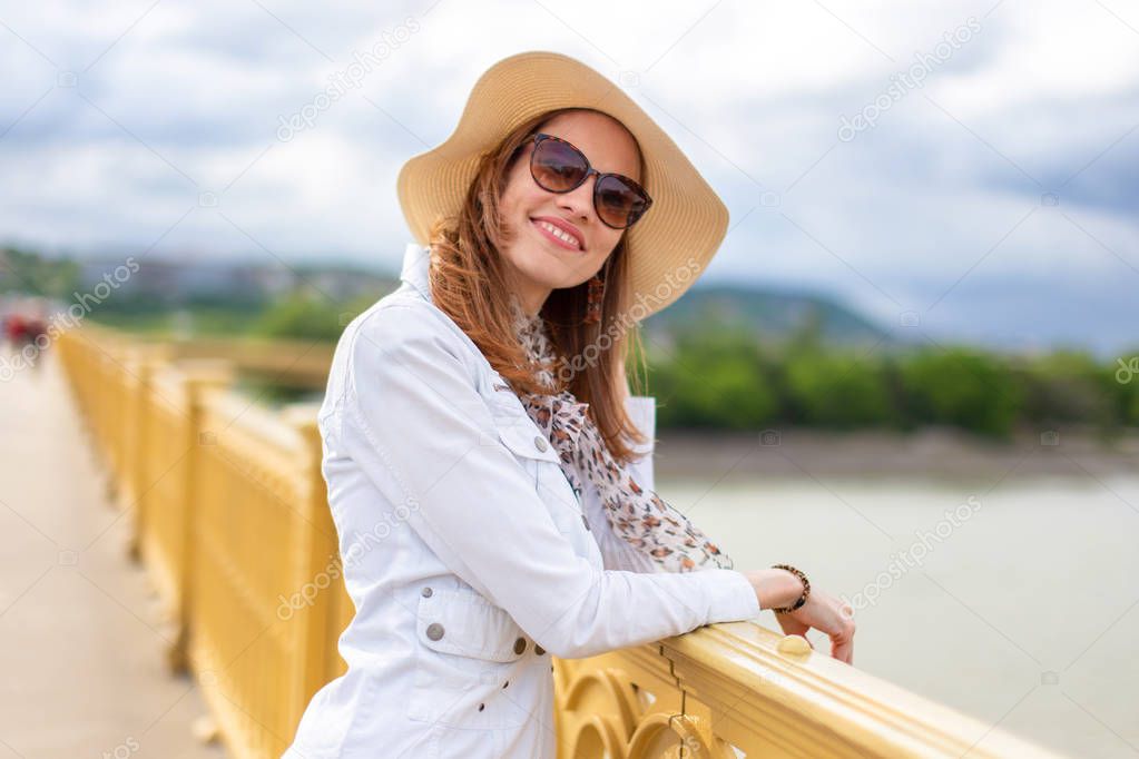 Natural beauty woman in hat smiling and relaxing on bridge