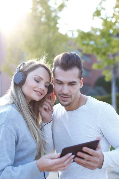 Young couple listening music by tablet and headphones