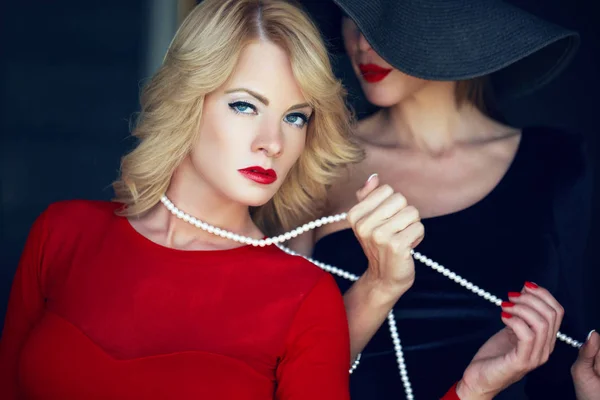 Femme blonde en rouge liée par un amant lesbienne sur des perles — Photo