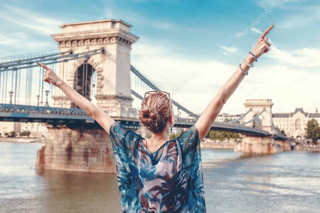 Young woman arms raised at Budapest panorama with Chain Bridge, Lanchid, visit Hungary