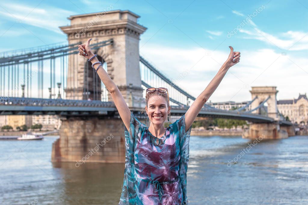 Happy young woman arms raised at Chain Bridge, Budapest, Hungary