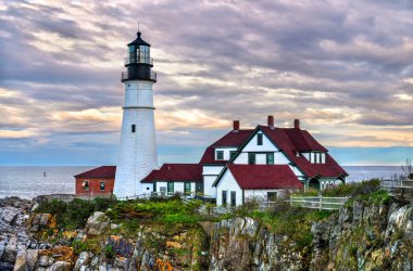 Maine, Cape Elizabeth 'teki tarihi Portland Baş Işığı. Deniz feneri, gün batımında Atlantik Okyanusu 'na bakan kayalık bir uçurumun üzerinde yer almaktadır.