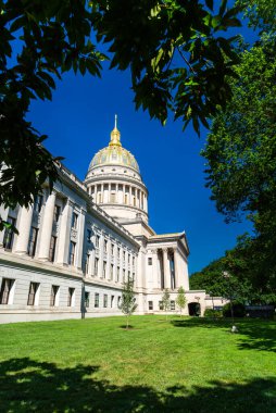 Batı Virginia Eyalet Kongre Binası Charleston, Batı Virginia, ABD. Mimar Cass Gilbert tarafından tasarlanan eser, güneşli bir günde ağaç yapraklarıyla çerçevelenmiş olarak burada görülen 23 ayar altın yapraklı kubbesiyle ünlüdür.