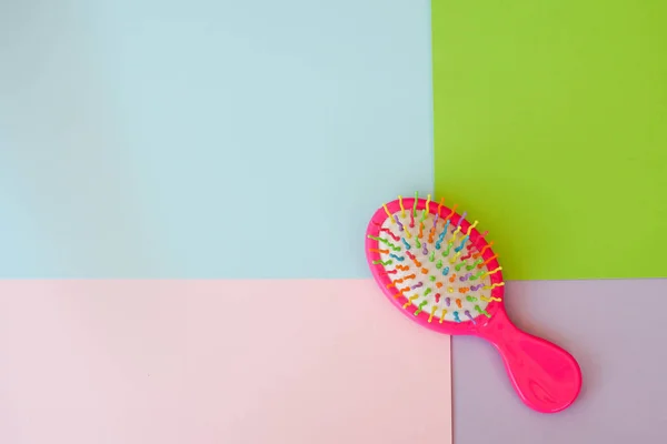 Pink children hair brush on color background.