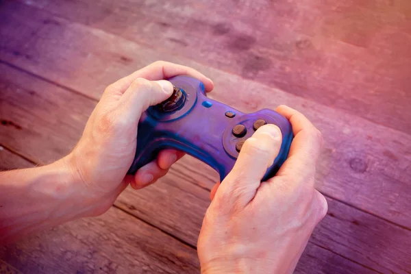 Blue joystick gamepad, game console on wooden background.