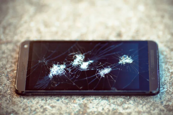 The broken phone screen on asphalt.