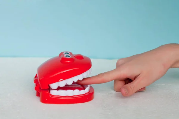 Some teeth biting a  finger on a blue background. The finger in