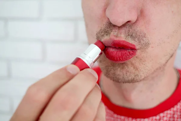 Portrait,   man with a bristle applying colorful red lip  lipsti