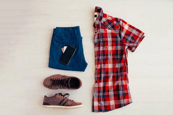 Red plaid shirt, jeans shorts and white sneakers on a white back