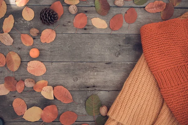 Knitted things and autumn leaves on a wooden background. Top vie