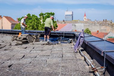 Isıtma ve alev tarafından bitüm yüzeyden Gaz Meşalesi erime. İşçi keçe çatı için Bitümlü kapak ayarlar, eritilmiş reçine ahşap aracı ile smear.