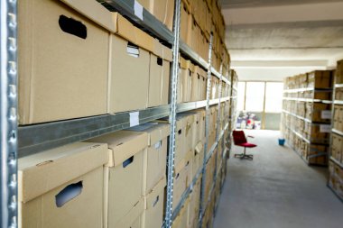 Dosya ve klasörleri ve belgeleri karton kutu arşiv, depolama odası ile raflardan yerleştirilen evrak yığını.