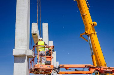 İşçi için derleme büyük inşaat beton kiriş yönetmek için Mobil vinç yardım ediyor.
