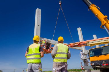 İşçi için derleme büyük inşaat beton kiriş yönetmek için Mobil vinç yardım ediyor.